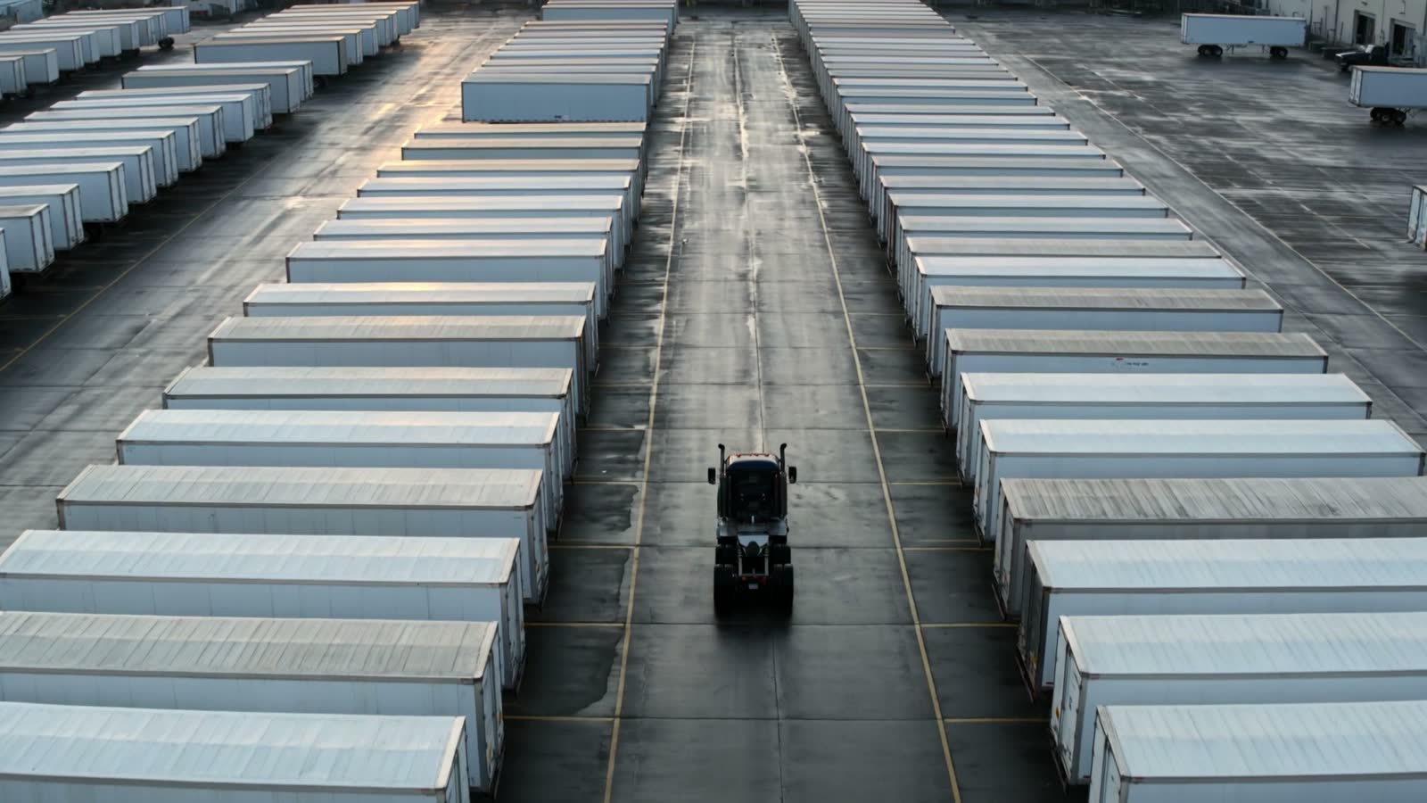 Rows of parked semi-trailers at a freight depot at dawn