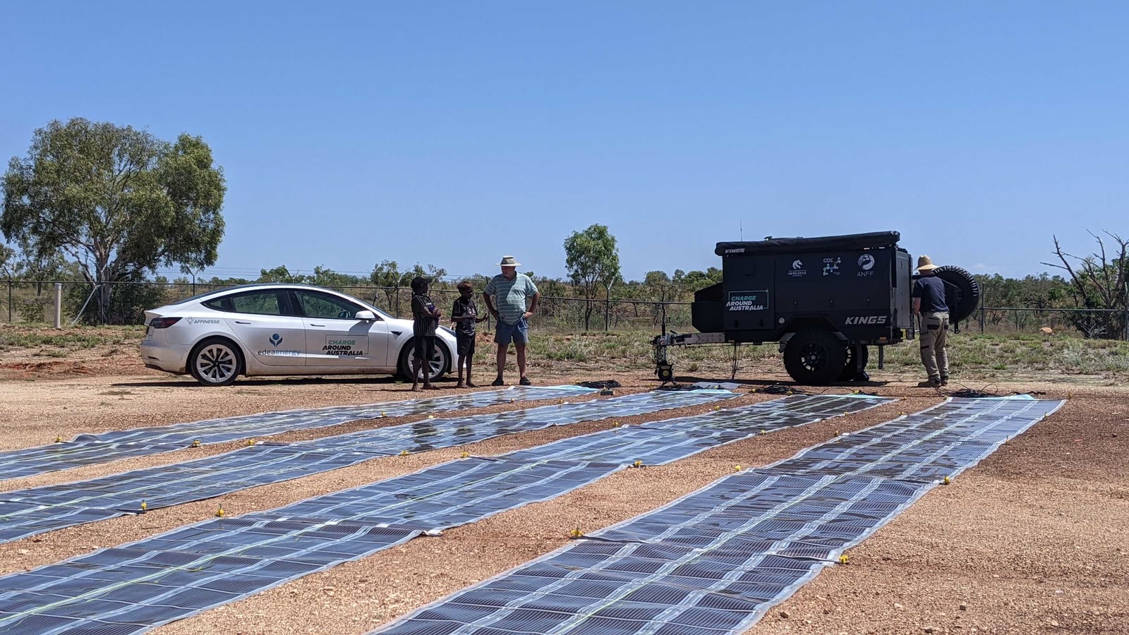 Printed Solar laid out on red ground beside an electric car during Charge Around Australia