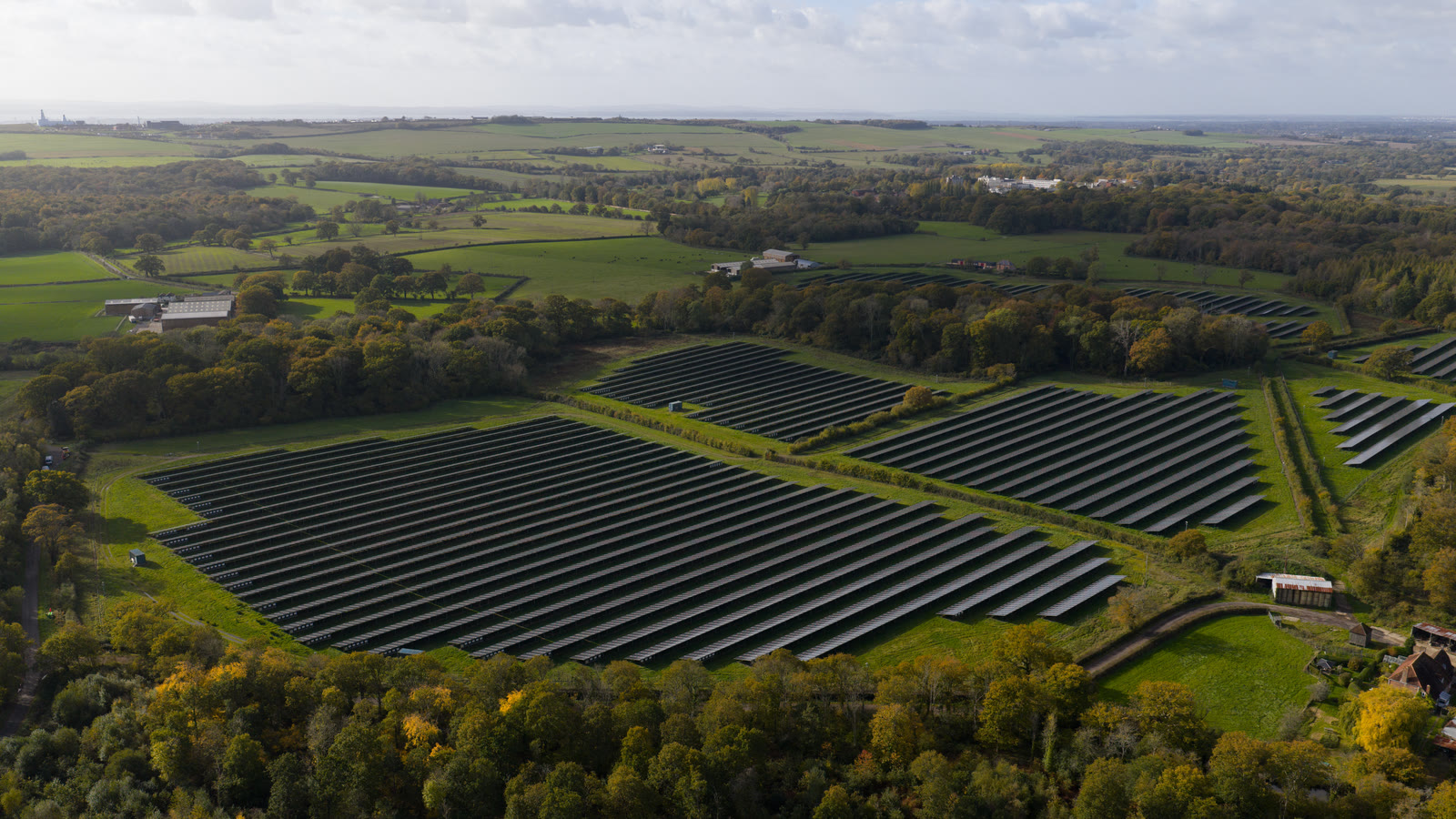 Aerial view of a solar farm among fields and woodland