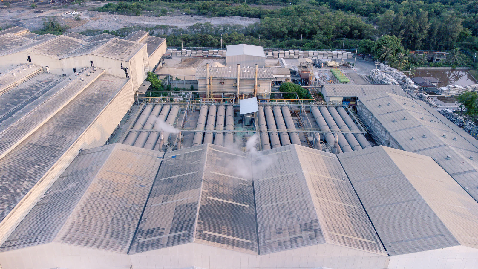 Aerial view of a large industrial site with long factory roofs
