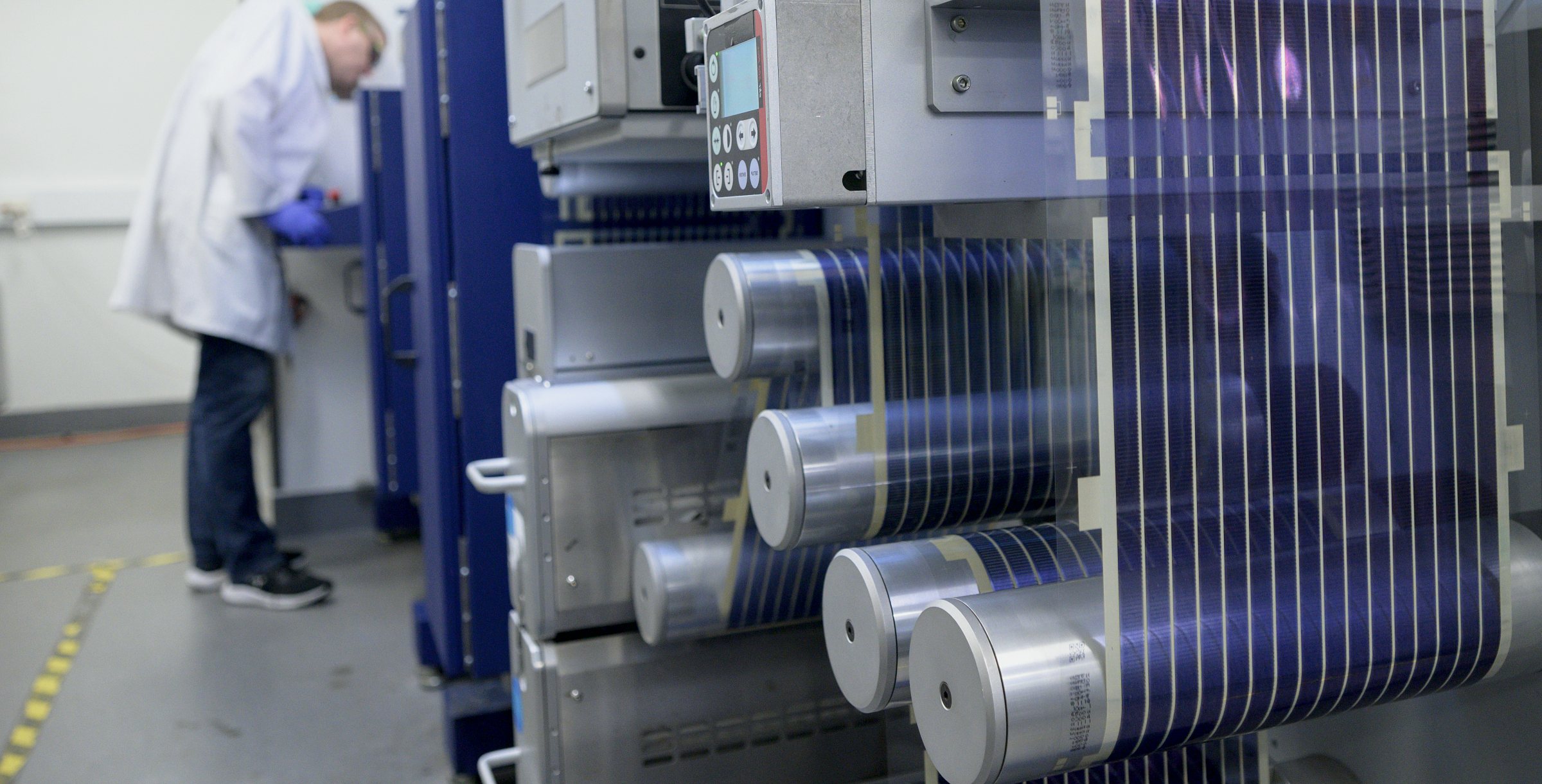 Printed Solar running over the rollers of the pilot press, with a researcher working behind